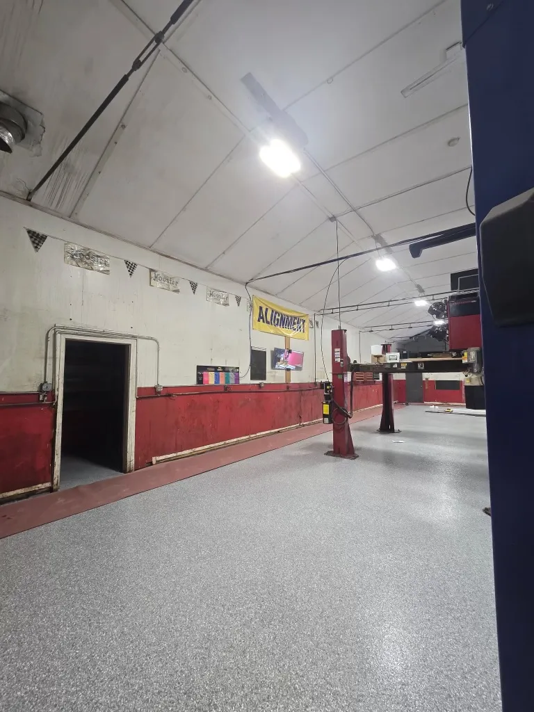 The repair bay before the repaint, stained cream walls above a scuffed oxblood wainscot