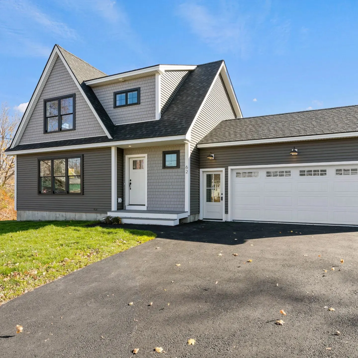 A gray-sided cape with white trim, black windows and an attached garage, finished and clear of equipment