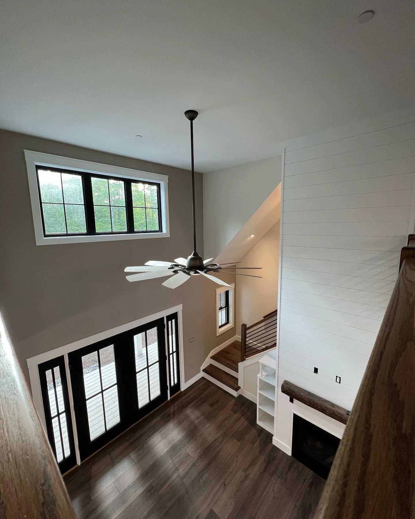 Two-story entryway painted by Nappi's Painting, with taupe walls, a white shiplap chimney chase, and black-framed windows and doors