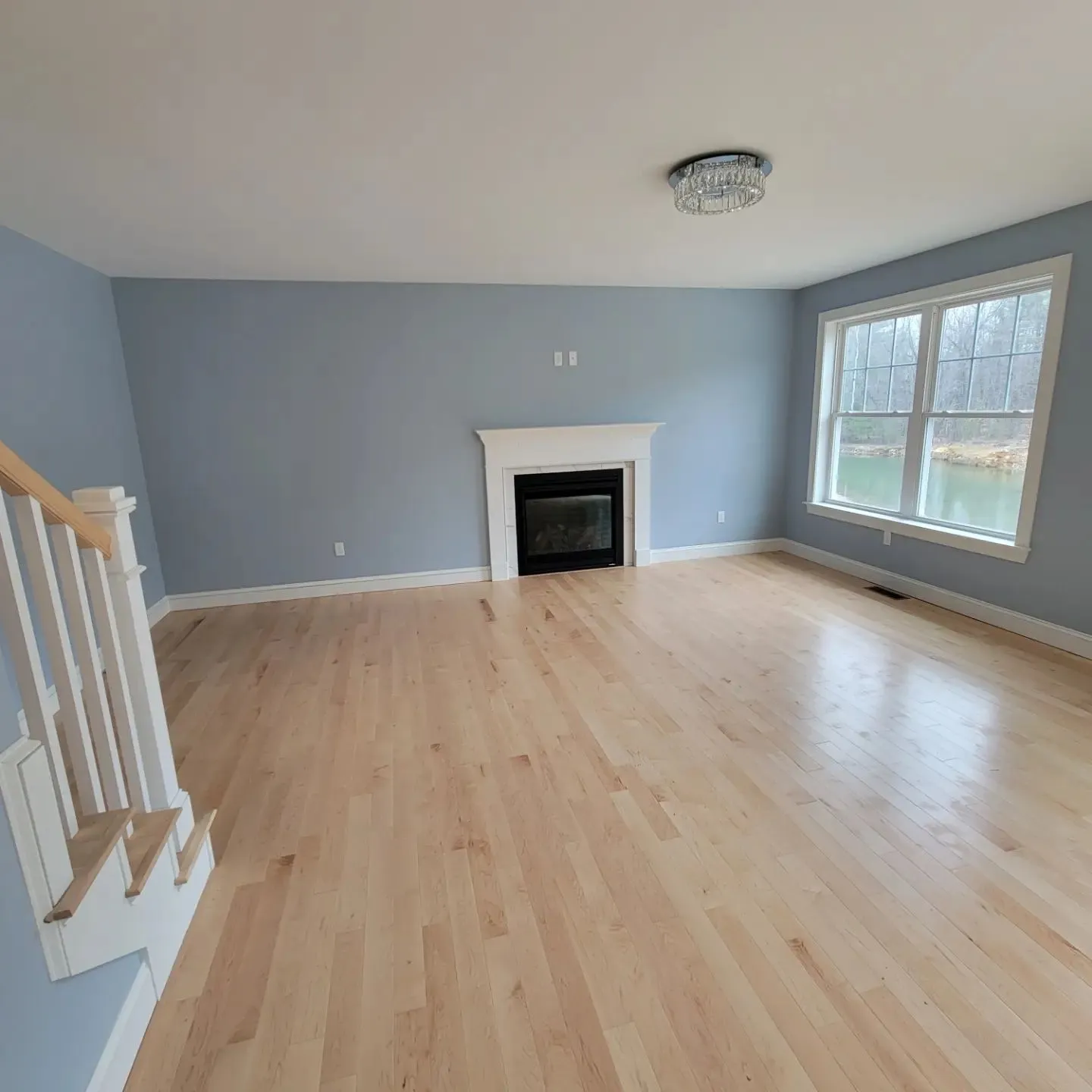 Living room painted in blue-grey with a white fireplace mantel, white trim, and a large window